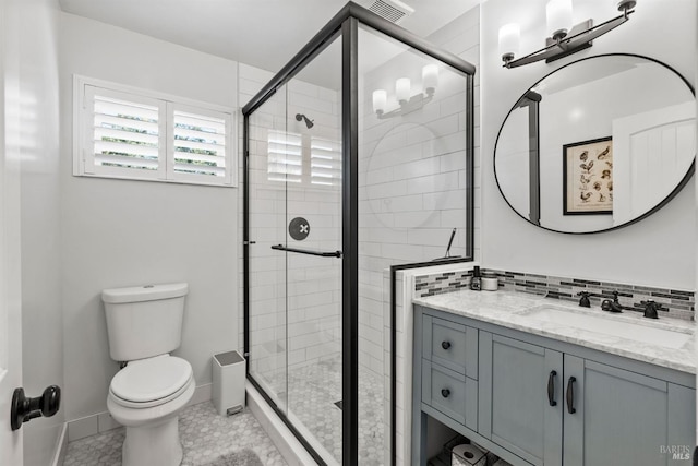 bathroom with vanity, tasteful backsplash, toilet, and walk in shower