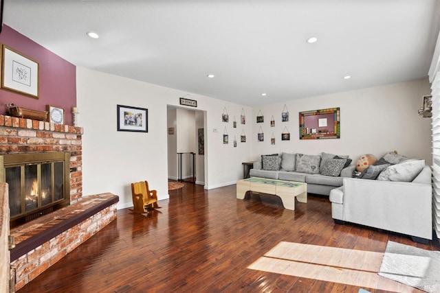 living room featuring dark hardwood / wood-style flooring and a brick fireplace