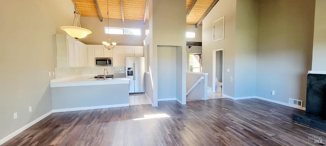 kitchen featuring pendant lighting, beamed ceiling, wood ceiling, white cabinetry, and appliances with stainless steel finishes