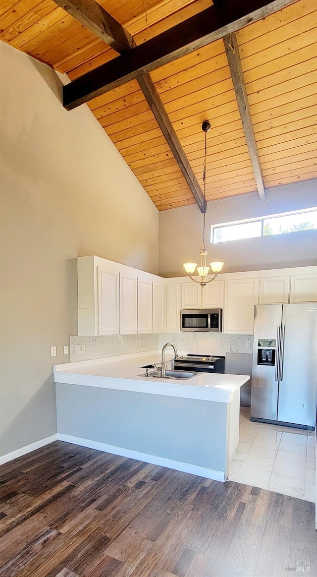 kitchen with white cabinets, kitchen peninsula, high vaulted ceiling, stainless steel appliances, and decorative light fixtures