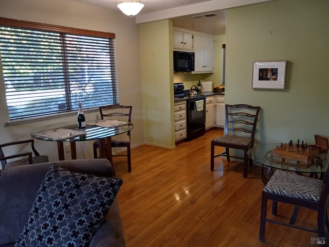 living area with light wood finished floors, baseboards, and visible vents