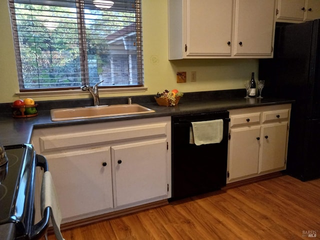 kitchen with white cabinets, a sink, a wealth of natural light, and black appliances