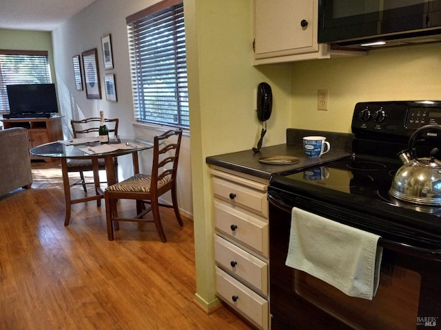 kitchen with dark countertops, light wood-style flooring, a wealth of natural light, and black / electric stove