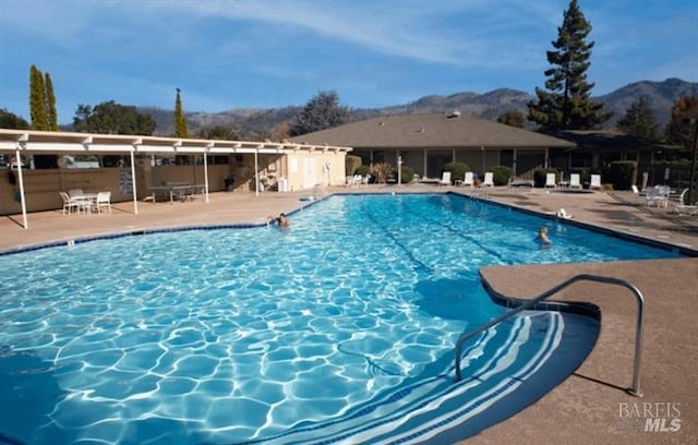 community pool with a patio area and a mountain view