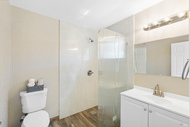 bathroom with toilet, a tile shower, vanity, and hardwood / wood-style floors