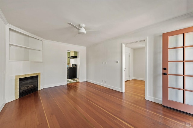 unfurnished living room with ornamental molding, ceiling fan, a fireplace, and hardwood / wood-style floors