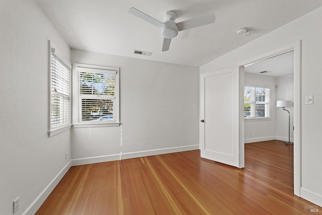 unfurnished bedroom with multiple windows, hardwood / wood-style floors, and ceiling fan