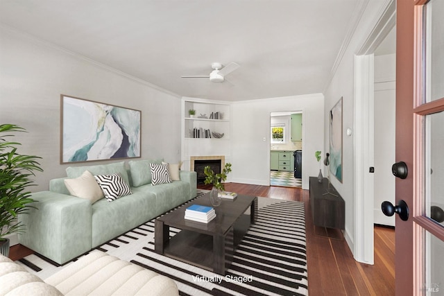 living room featuring ceiling fan, ornamental molding, dark hardwood / wood-style flooring, and built in shelves