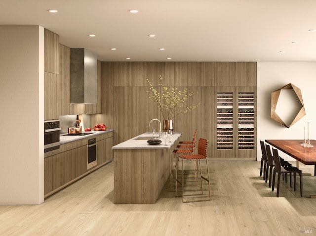 kitchen featuring an island with sink, light wood-type flooring, and stainless steel oven