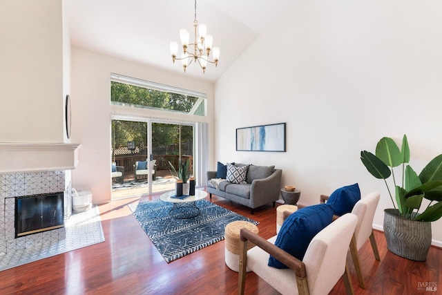 living room featuring a chandelier, a tile fireplace, high vaulted ceiling, and wood finished floors