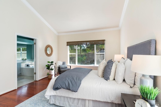 bedroom featuring lofted ceiling, ornamental molding, ensuite bath, wood finished floors, and baseboards