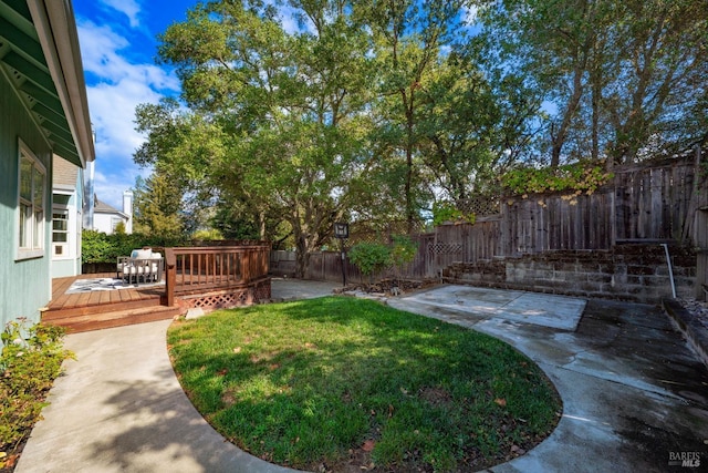 view of yard featuring a patio area, a fenced backyard, and a wooden deck