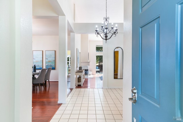 entryway featuring light tile patterned floors, baseboards, and an inviting chandelier