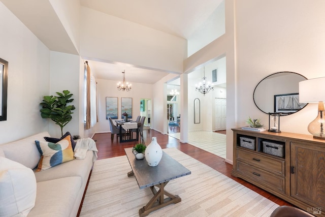 living room featuring a high ceiling, a notable chandelier, wood finished floors, and baseboards