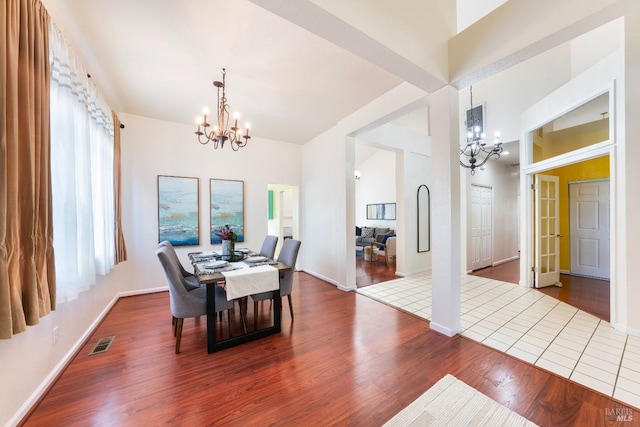 dining area with baseboards, wood finished floors, visible vents, and a chandelier