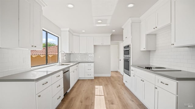 kitchen with white cabinets, sink, appliances with stainless steel finishes, light wood-type flooring, and decorative backsplash