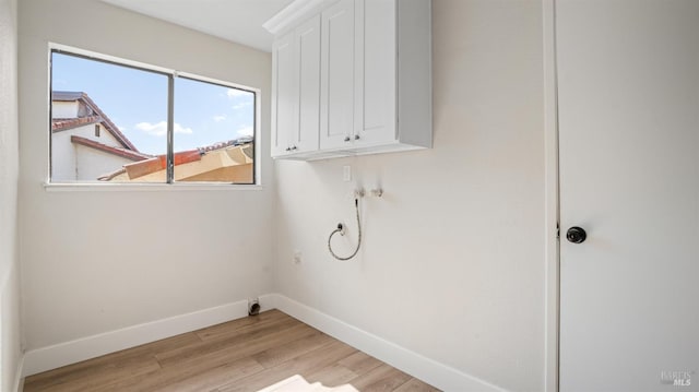 clothes washing area featuring washer hookup, light hardwood / wood-style flooring, and cabinets