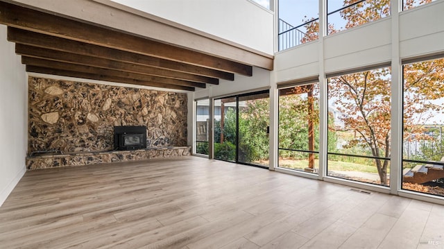 unfurnished sunroom with a wood stove and beamed ceiling