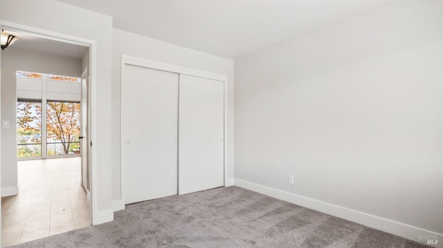 unfurnished bedroom with a closet and light colored carpet