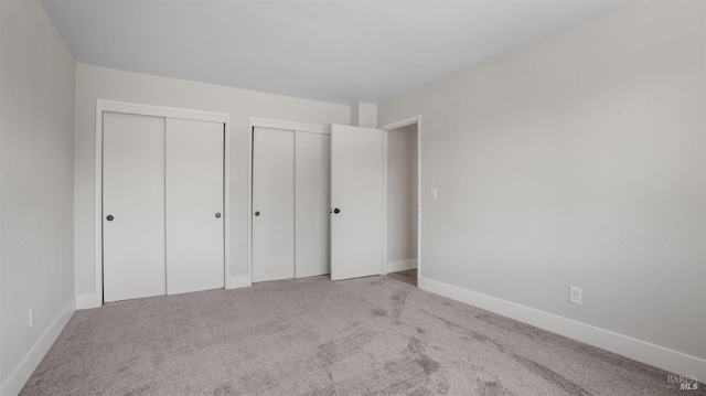 unfurnished bedroom with light carpet and two closets