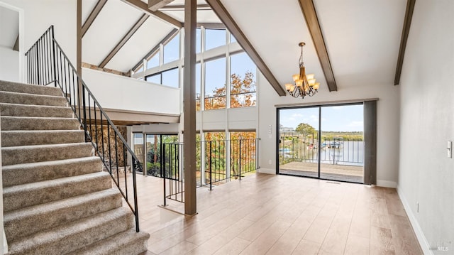 unfurnished living room featuring wood-type flooring, a water view, plenty of natural light, and high vaulted ceiling