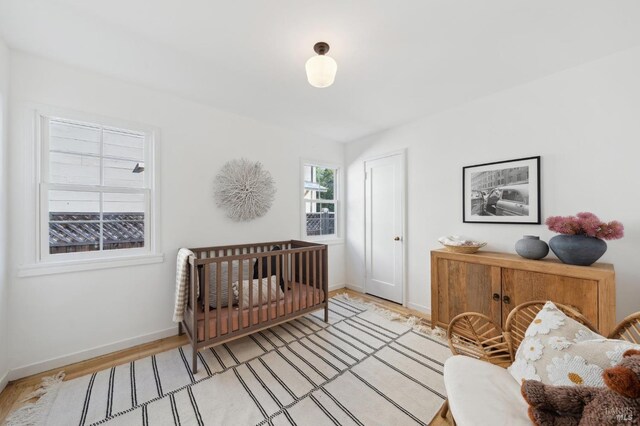 bedroom featuring a nursery area and light hardwood / wood-style floors