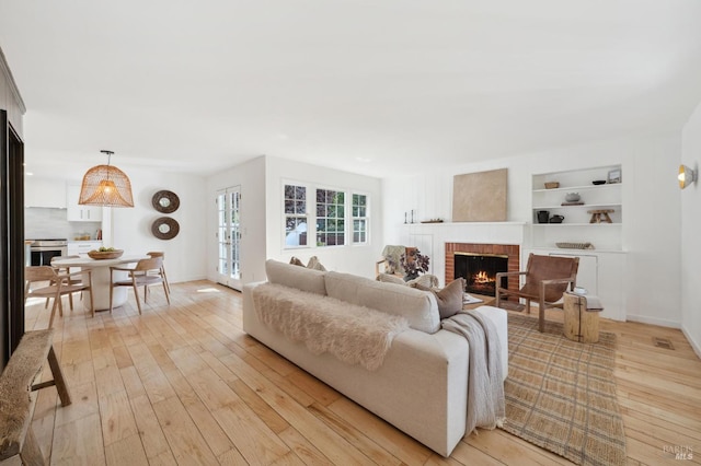 living room featuring light hardwood / wood-style floors, a fireplace, and built in shelves