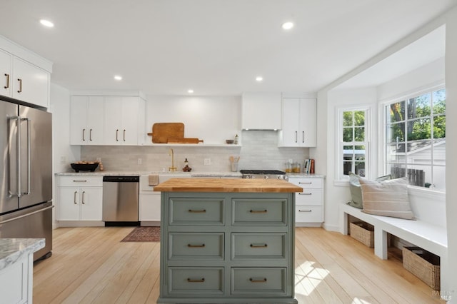 kitchen featuring stainless steel appliances, butcher block countertops, decorative backsplash, and white cabinetry