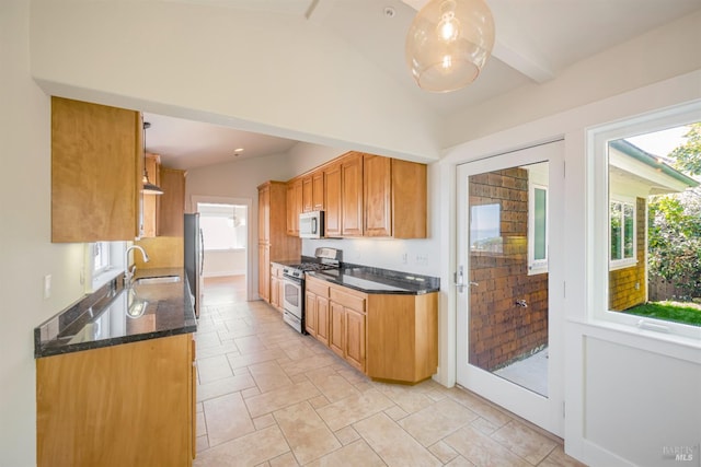 kitchen with lofted ceiling with beams, stainless steel appliances, dark stone counters, and sink