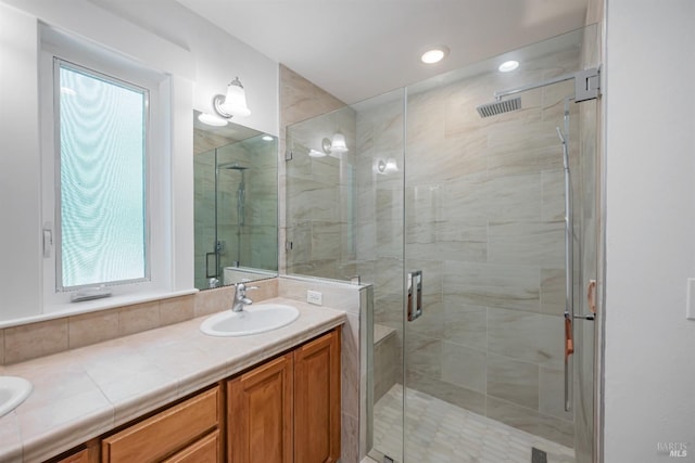 bathroom featuring a wealth of natural light, vanity, and a shower with door