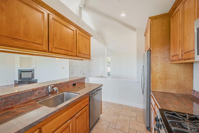 kitchen featuring lofted ceiling, light tile patterned floors, sink, appliances with stainless steel finishes, and dark stone countertops