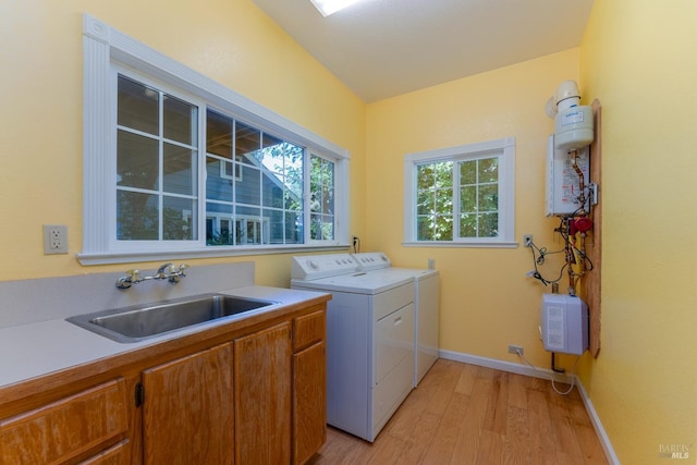 clothes washing area featuring independent washer and dryer, cabinets, sink, and light wood-type flooring