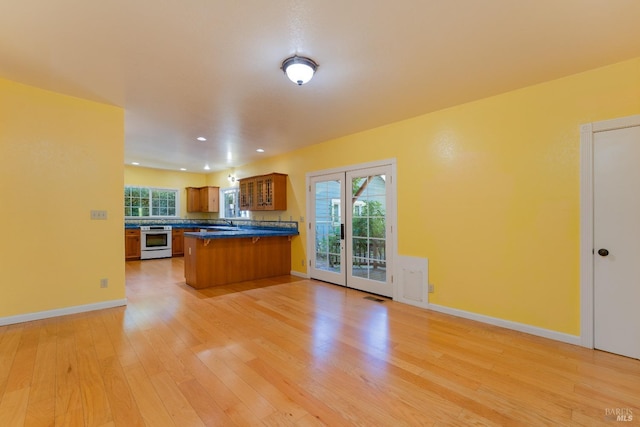 kitchen featuring stainless steel range oven, sink, a kitchen breakfast bar, kitchen peninsula, and light hardwood / wood-style floors