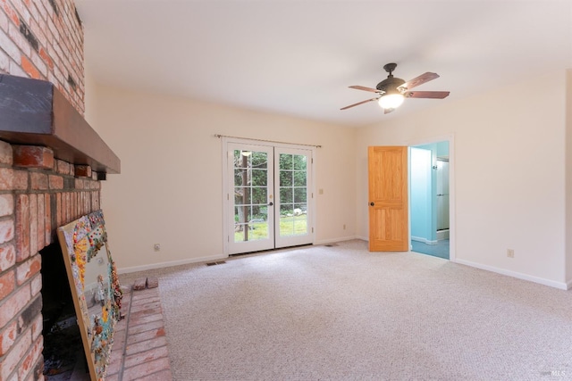 unfurnished living room featuring light carpet, a brick fireplace, french doors, and ceiling fan