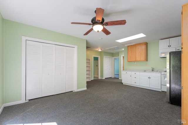 kitchen featuring sink, stainless steel refrigerator, dark colored carpet, white cabinets, and white range with gas cooktop