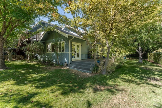 view of side of home with french doors, a deck, and a lawn