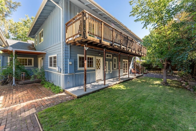 rear view of property featuring a patio, a deck, and a lawn