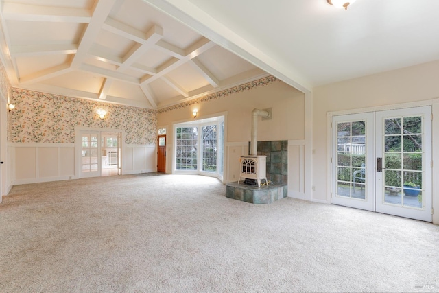 unfurnished living room featuring vaulted ceiling with beams, carpet flooring, coffered ceiling, french doors, and a wood stove