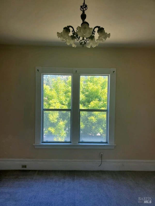 unfurnished room with carpet and a chandelier