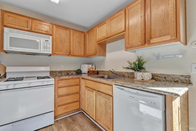 kitchen featuring a sink, light brown cabinetry, white appliances, and light wood-style floors