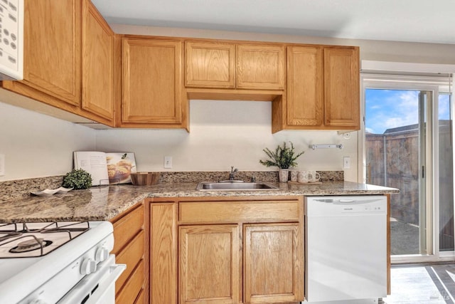 kitchen with a sink, white appliances, and light stone countertops