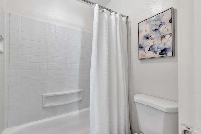 full bath with toilet, shower / tub combo with curtain, and a textured wall