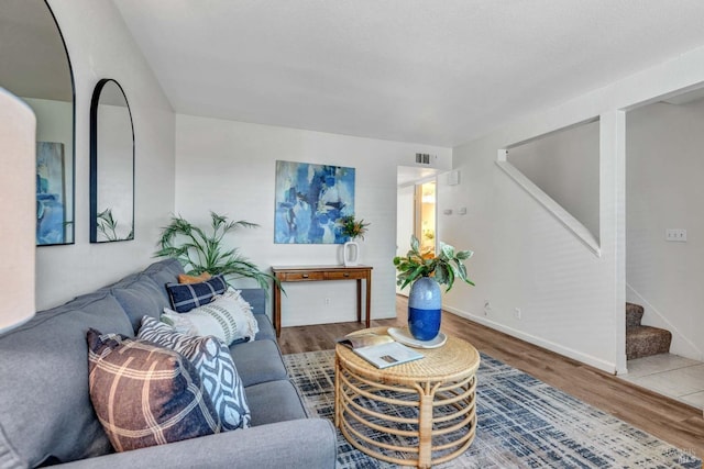 living area featuring wood finished floors, baseboards, visible vents, and stairway