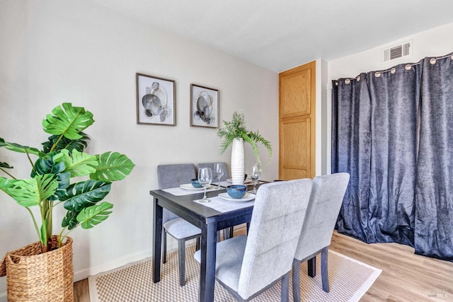 dining room with visible vents, light wood-style flooring, and baseboards