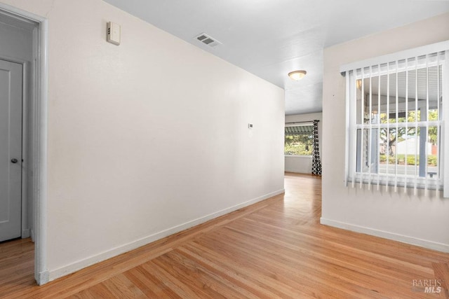 corridor with baseboards, visible vents, and wood finished floors