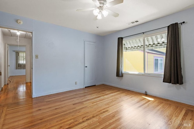 spare room with visible vents, light wood-type flooring, attic access, and baseboards