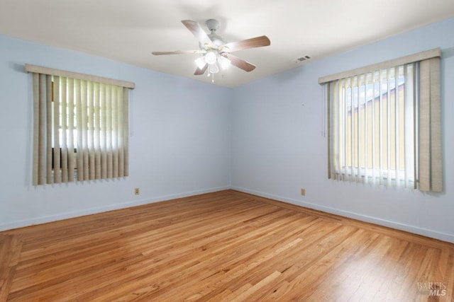 empty room with visible vents, baseboards, light wood-type flooring, and a ceiling fan