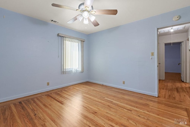 empty room with visible vents, a ceiling fan, baseboards, light wood-type flooring, and attic access