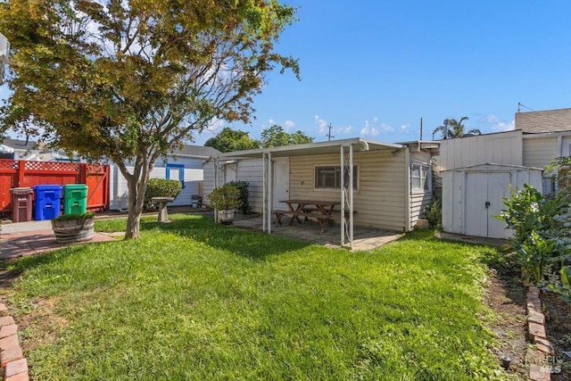 back of property featuring a shed, a yard, fence, an outdoor structure, and a patio