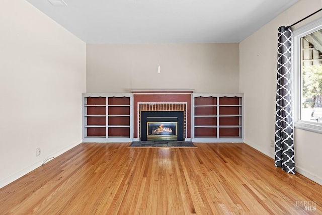 unfurnished living room featuring a fireplace with flush hearth, light wood-type flooring, and baseboards